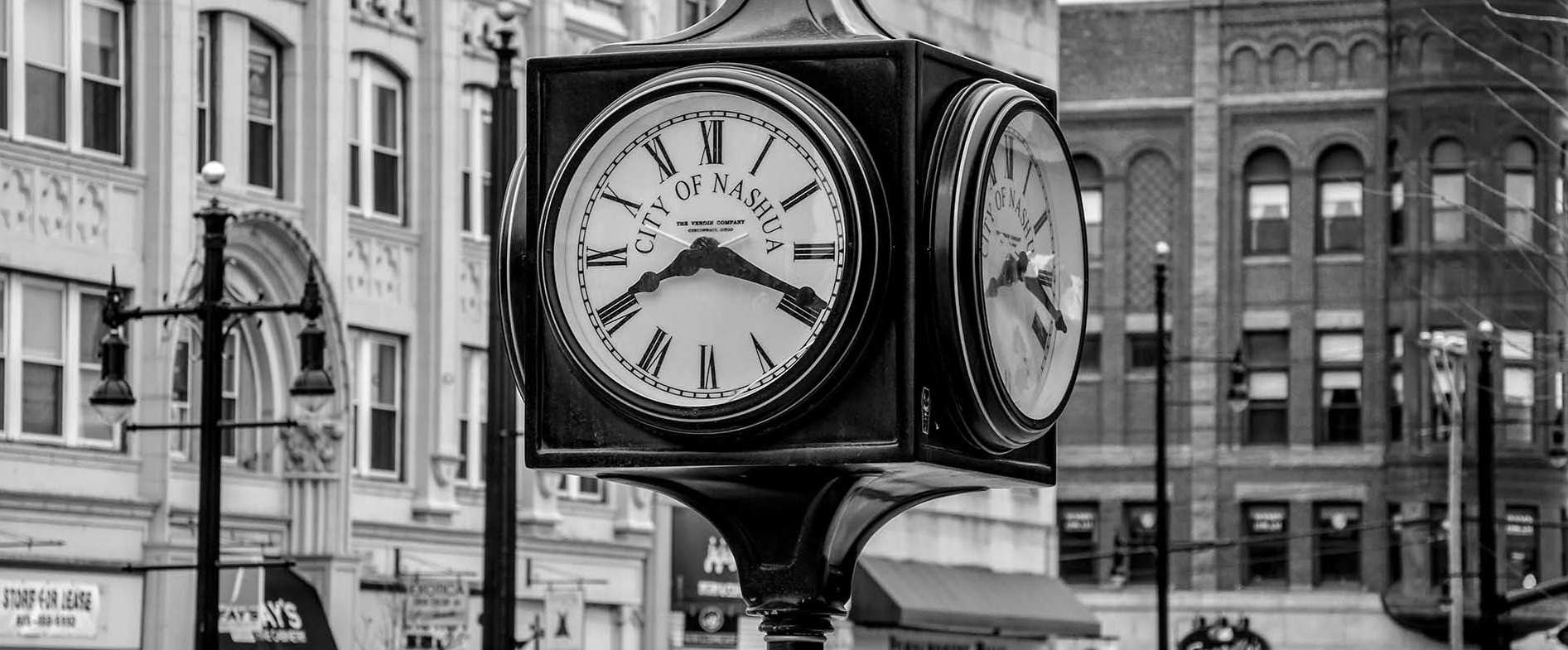 Black-and-white photo of the iconic Nashua street clock, representing the heart of the local business district